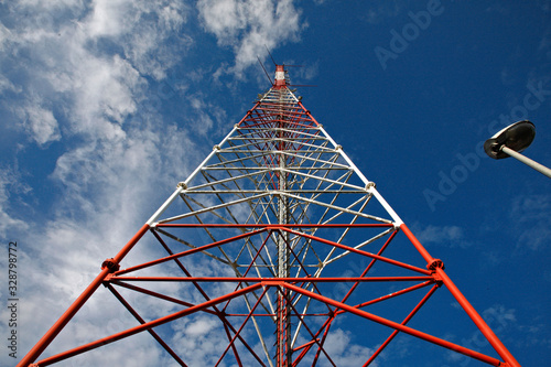 tall metal constructed comunication tower at beautiful blue sky with fluffy clouds background photo