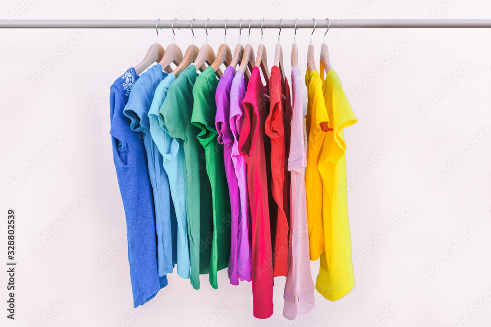 Clothes hanging on clothing rack wardrobe fashion apparel selection of  rainbow color t-shirts on closet hangers. Womens wear in store shopping  spring cleaning concept. Summer home wardrobe. Stock Photo
