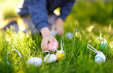 Little boy hunting for easter egg in spring garden on Easter day. Focus on multicolor eggs.