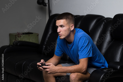 Young Caucasian Teenage Man Addicted to Playing Video Games Sitting On Couch photo