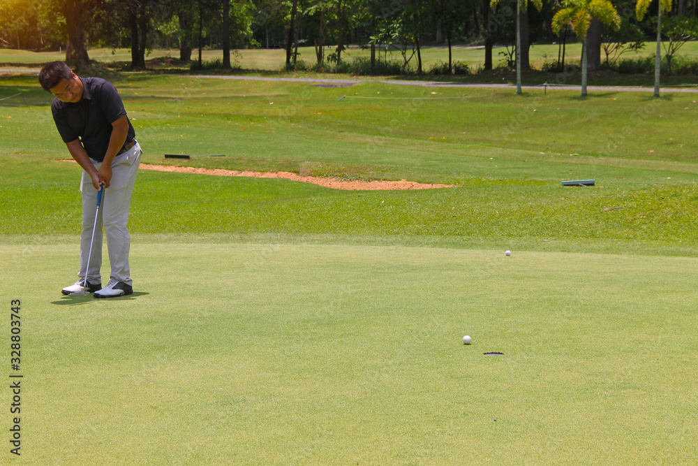 Obraz premium Golfer putting golf into the hole in beautiful golf course. The evening golf course with sunset ibackground.