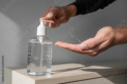 Hand sanitizer alcohol gel rub clean hands hygiene prevention of coronavirus virus outbreak. Man using bottle of antibacterial sanitiser soap.