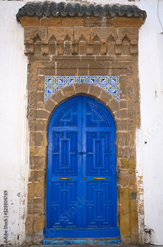 Fresh painted blue door with stonework and tiles in Essaouira Medina on white building