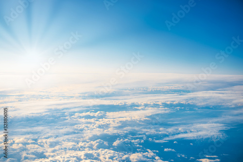 Aerial view of blue sky with sunset sun, white fluffy cumulus clouds