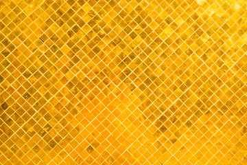 Closeup view of wall surface with many gold shiny mosaic squares. Саn be used as metallic background