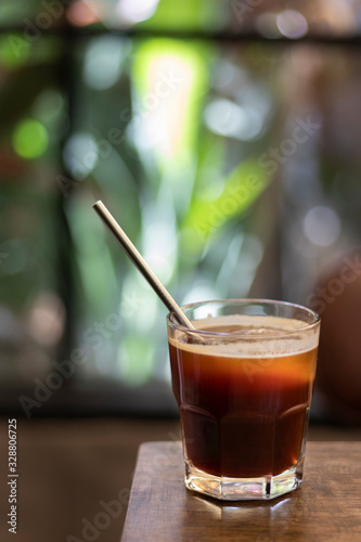 iced black coffee with metal straw on a wooden table in a coffee shop