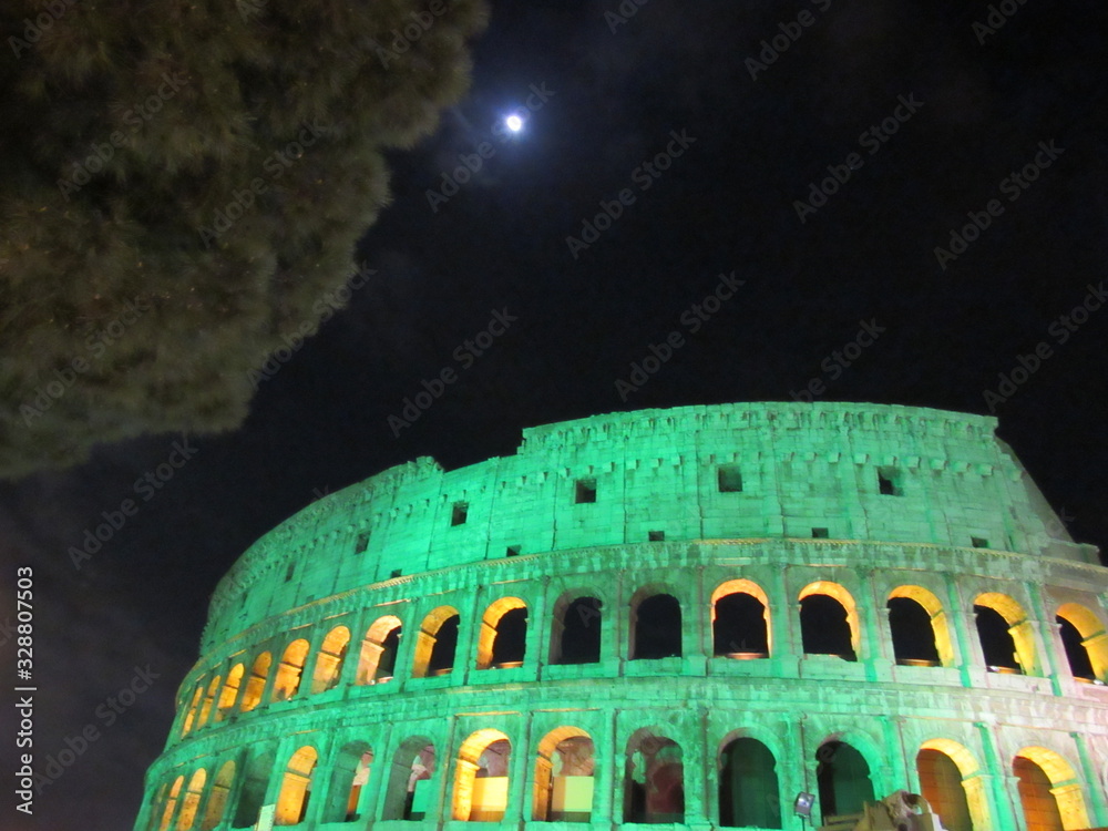 The Roman Colosseum lit up green at night for Saint Patricks' Day in Italy