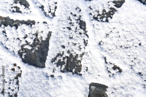 Black stone ground after snow
