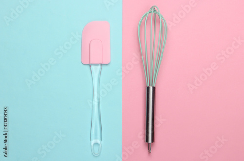 Kitchen spatula and whisk on pink blue pastel background. Minimalism. Top view