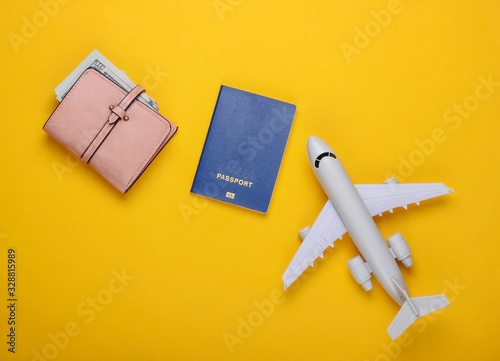 Flat lay travel composition on yellow background. Plane figurine, passport, wallet with dollars. Recreation, vacation and tourism, minimalism concept. Top view