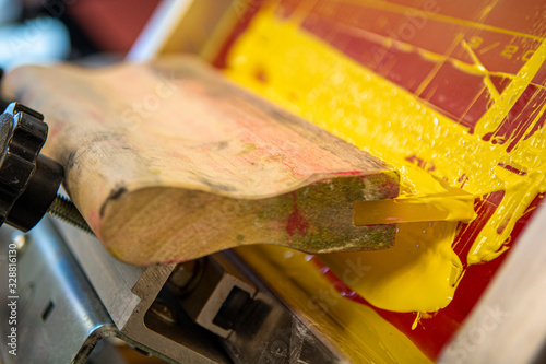 Screen printing squeegee resting in a silk screen setup
