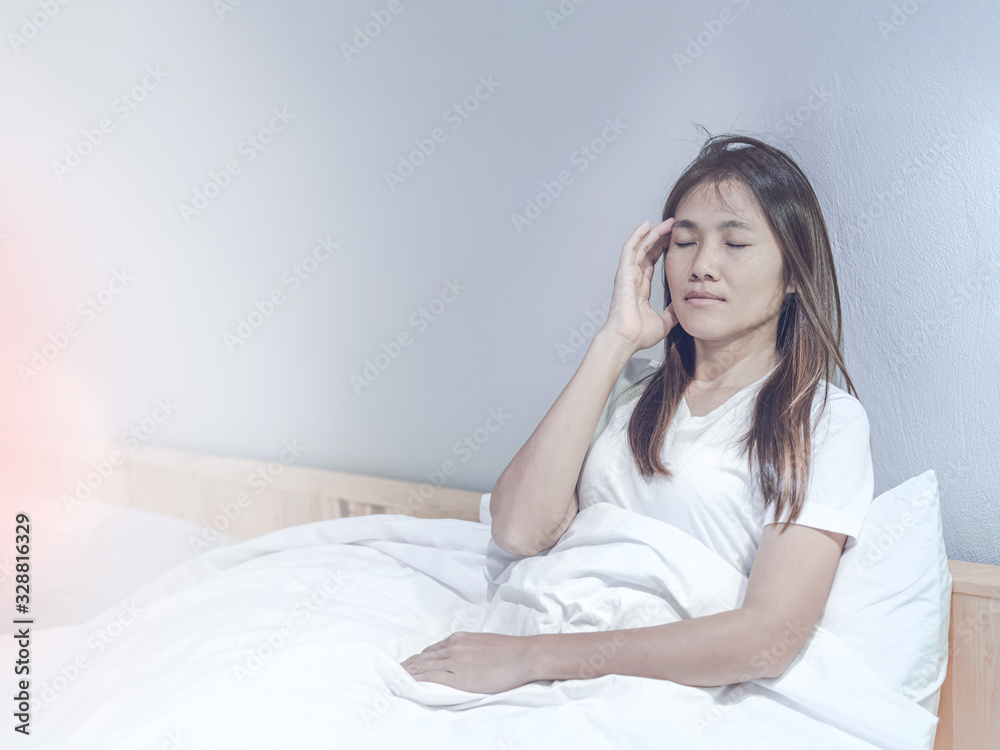 Young asian woman feeling headache and discomfort on white bed in her bedroom. Young asian woman feeling headache and discomfort on white bed in her bedroom.