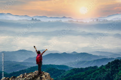 Young traveler standing on top of cliff on mountains at sunrise in the morring.
