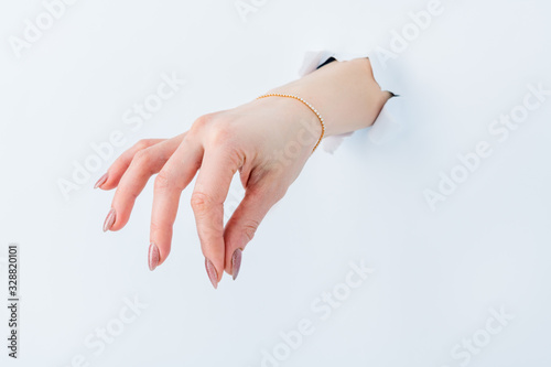 women's hand through hole in white paper