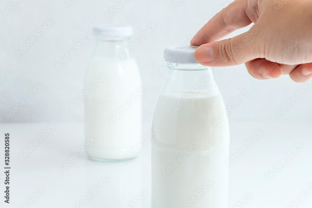 Woman hand's holding a cap of glass bottle milk isolated on white table background for food and healthy concept. with copy space for text. Woman hand's holding a cap of glass bottle milk isolated on white table background for food and healthy concept. with copy space for text.