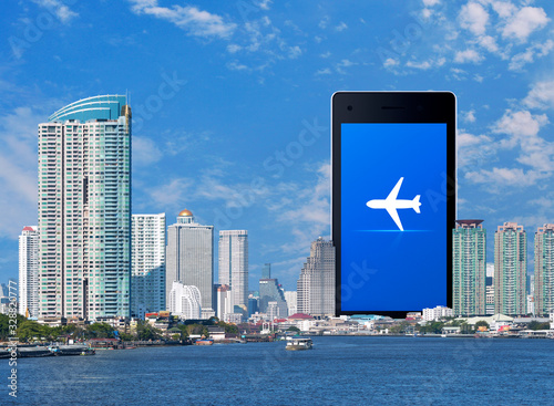 Airplane flat icon on modern smart mobile phone screen over office city tower, river, skyscraper and blue sky, Business plane transportation online concept