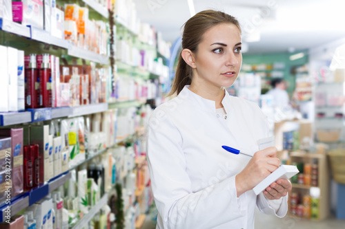 Female pharmacist is attentively checking medicine with notebook Free Download Female pharmacist is attentively checking medicine with notebook - GFXLoad