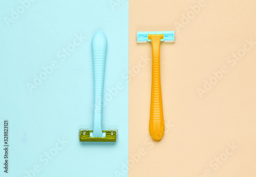Minimalistic beauty concept. Two plastic razor on blue yellow pastel background. Top view photo