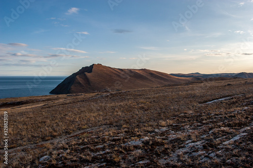 View of the shore of Lake Baikal. Brown rocks in the shade. Evening, sunset.
