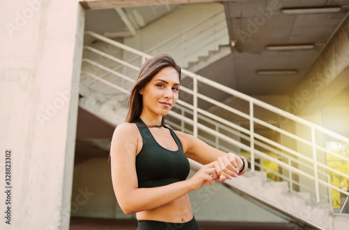Attractive sport woman in sportswear use smart watch outdoors at urban environment