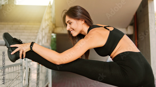 Sporty woman doing stretching leg before jogging among the urban environment