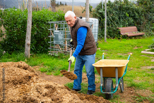 Senior man preparing manure for fertilizing land