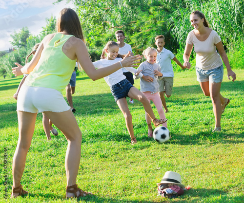 People with kids together outdoors playing football