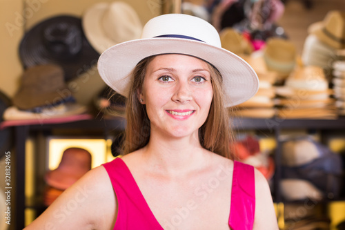 young blonde woman choose straw hat in shop