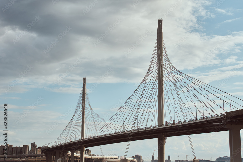 modern cable stayed bridge over the river against cloudy sky. Engineering construction closeup