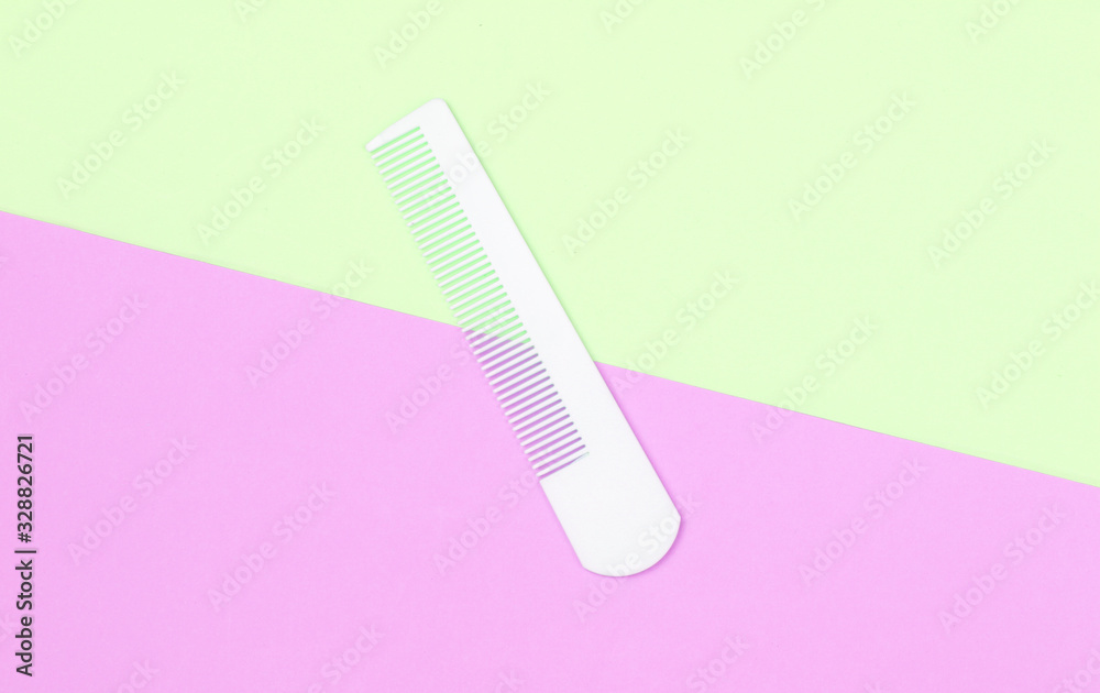 White plastic comb on coloored pastel background. Hair care, beauty concept. Top view
