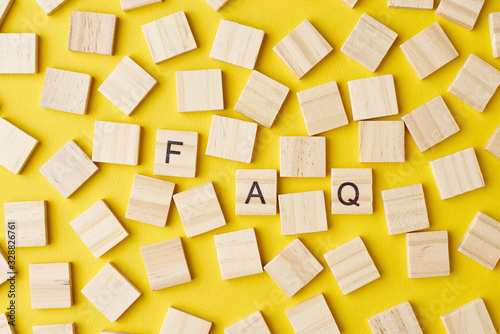 Wooden blocks with abbreviation FAQ on the yellow background, top view. Frequently asked questions concept