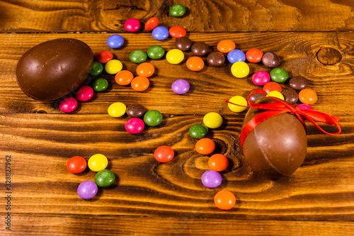 Chocolate easter eggs and multicolored candies on wooden table