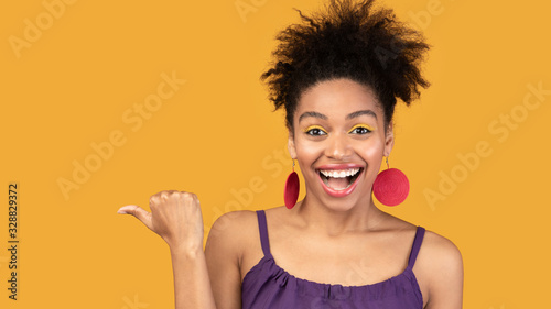 Excited black woman pointing finger at free space