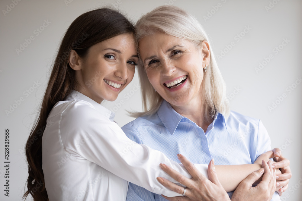 Head shot portrait of happy mature mother and grown-up daughter hugging cuddling posing for family picture together, smiling senior mom and adult girl show love and care, enjoy time together Head shot portrait of happy mature mother and grown-up daughter hugging cuddling posing for family picture together, smiling senior mom and adult girl show love and care, enjoy time together