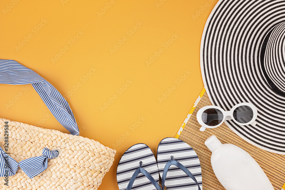 Flat lay with summer accessories for woman. Sun hat, sunglasses, sunscreen protection, flip flops and bag. Summer travel, vacatoins, heat protection concept. Copy space