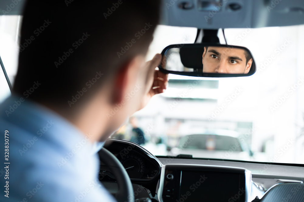 Guy Checking Mirrors Sitting In Driver's Seat In Dealership Store Guy Checking Mirrors Sitting In Driver's Seat In Dealership Store