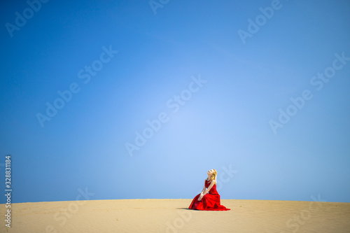 赤いドレスを着て砂丘に立つ白人女性 © Y.S Graphics