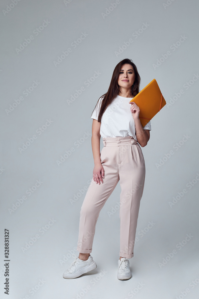 girl student stands with an orange folder thoughtfully and smile girl student stands with an orange folder thoughtfully and smile