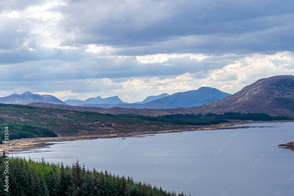 Beautiful layers of color of rural Isle of Skye landscape on an overcast day. From loch shore at low tide to the rolling hills of the countryside and the Cuillin mountain range