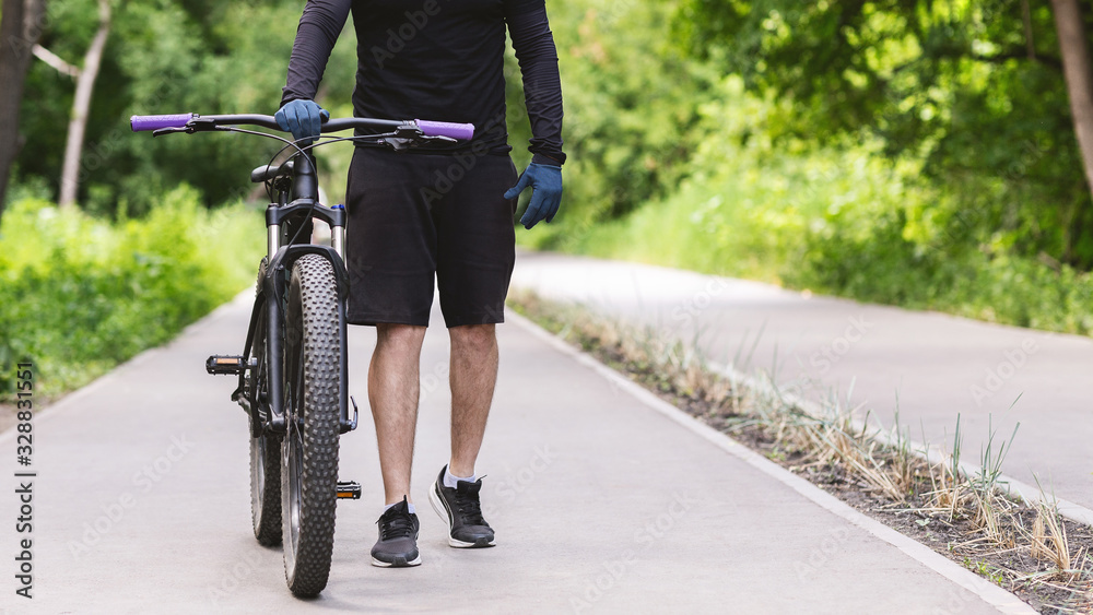 Fototapeta premium Cropped image of cycler holding bike in public park