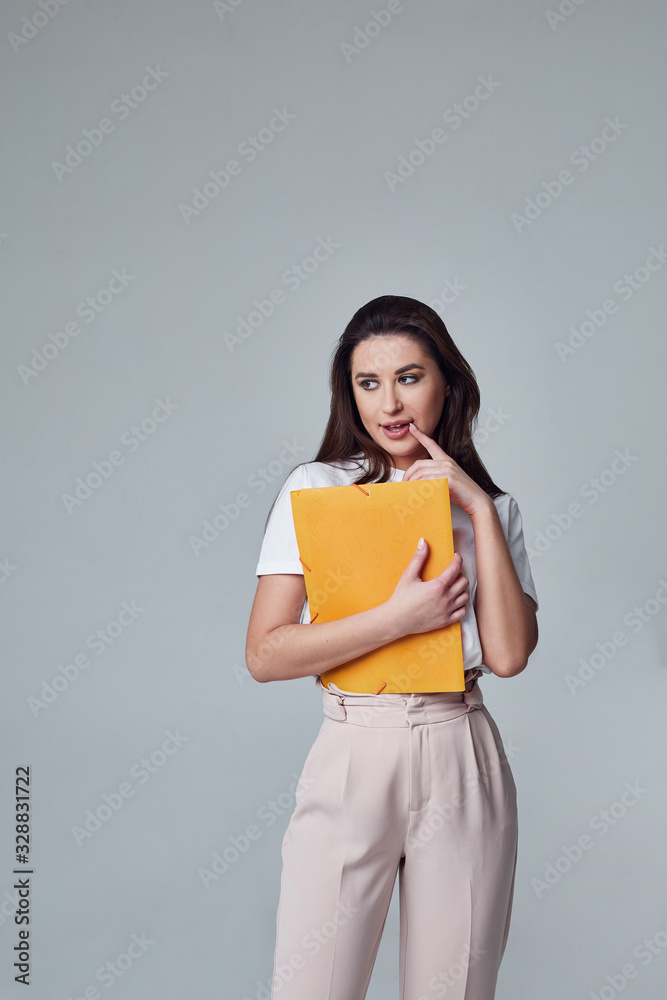girl student stands with an orange folder thoughtfully and smile girl student stands with an orange folder thoughtfully and smile