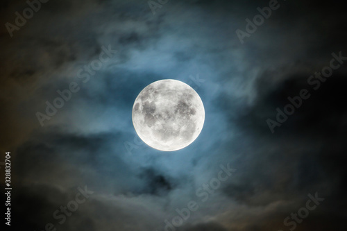 A full moon lights up a blanket of clouds