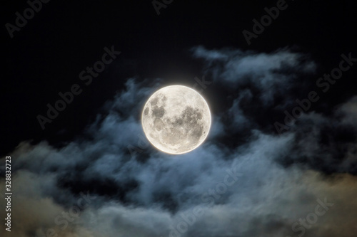 The full moon, with wispy white clouds around it