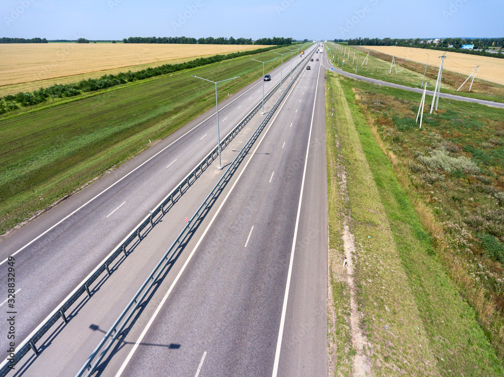 Fototapeta premium Wide highway with four lanes, aerial view at straight motorway in agricultural fields. Russia