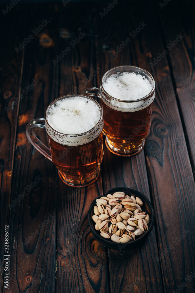 Appetizing salty beer snacks. Two mugs of craft lager and pistachios. Oktoberfest food, pub concept Appetizing salty beer snacks. Two mugs of craft lager and pistachios. Oktoberfest food, pub concept