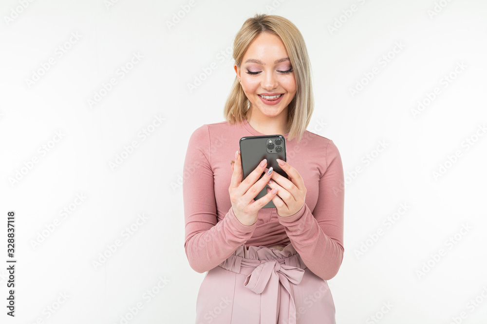 cute blond girl with a phone in her hands on a white background with copy space cute blond girl with a phone in her hands on a white background with copy space