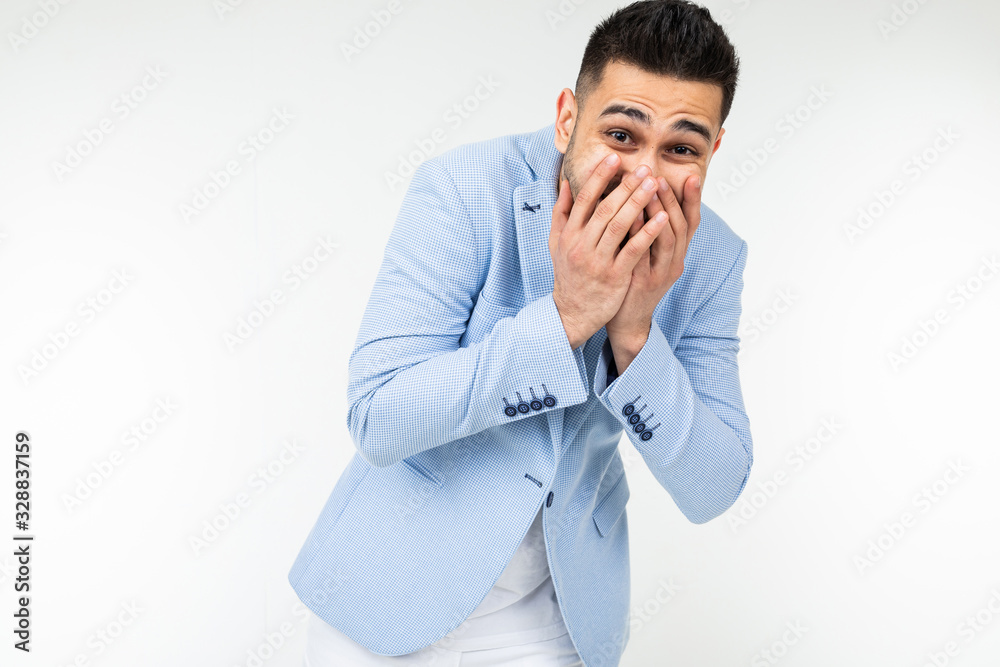 handsome man in classic style laughs covering his face with his hand on a white studio background handsome man in classic style laughs covering his face with his hand on a white studio background