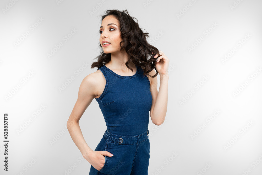 attractive girl in denim overalls posing on a white background attractive girl in denim overalls posing on a white background