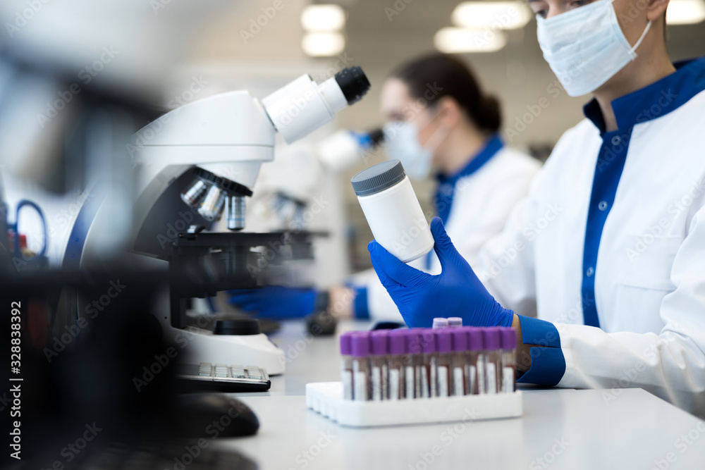 Male scientist holding white bottle of pills Male scientist holding white bottle of pills