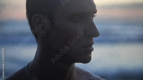 Portrait close up of a young caucasian man enjoying free time on a beach by the sea at sunset on the evening